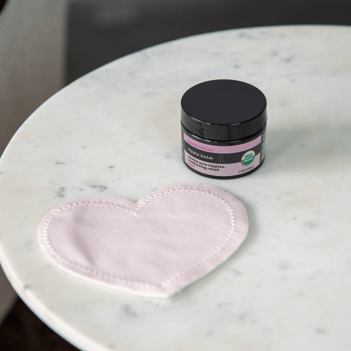 Image of nipple balm and washable nursing pad on a table