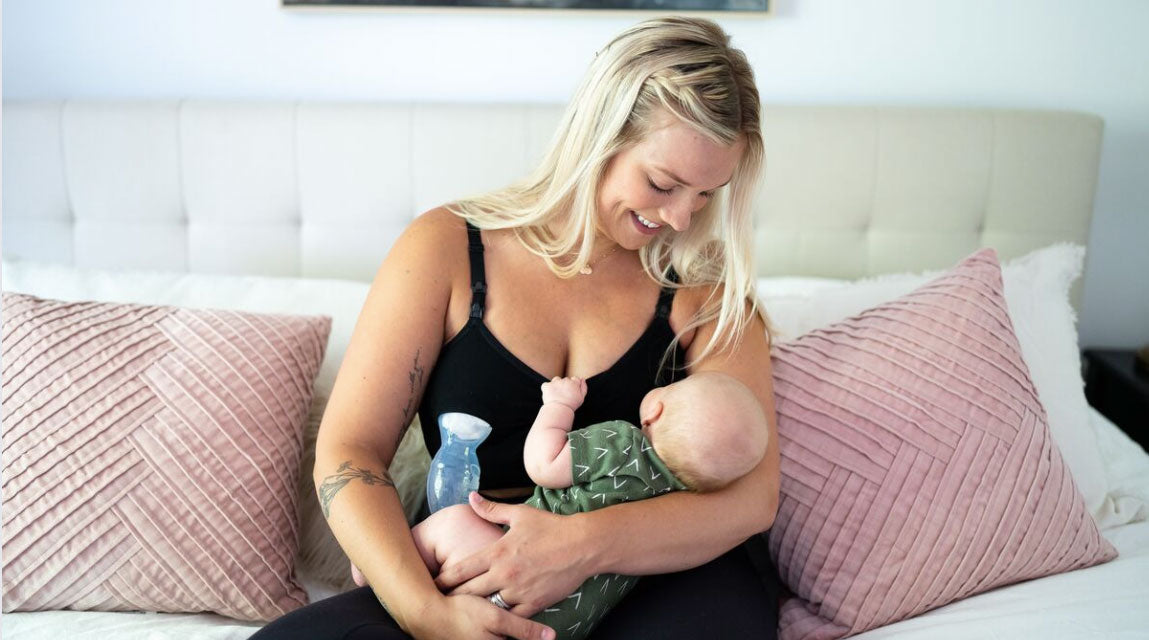 woman pumping and holding baby