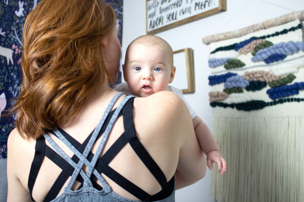 Back of woman wearing heather grey nursing tank top holding a baby